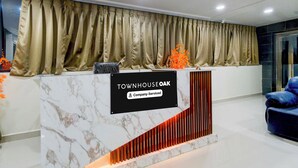 En receptionsdisk med en marmorskiva, en skylt med texten ”TOWNHOUSE OAK & Company Serviced” och en blå stol till höger.