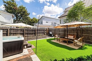 Ein Garten mit Whirlpool, Terrassenmöbeln und einem Holzzaun.