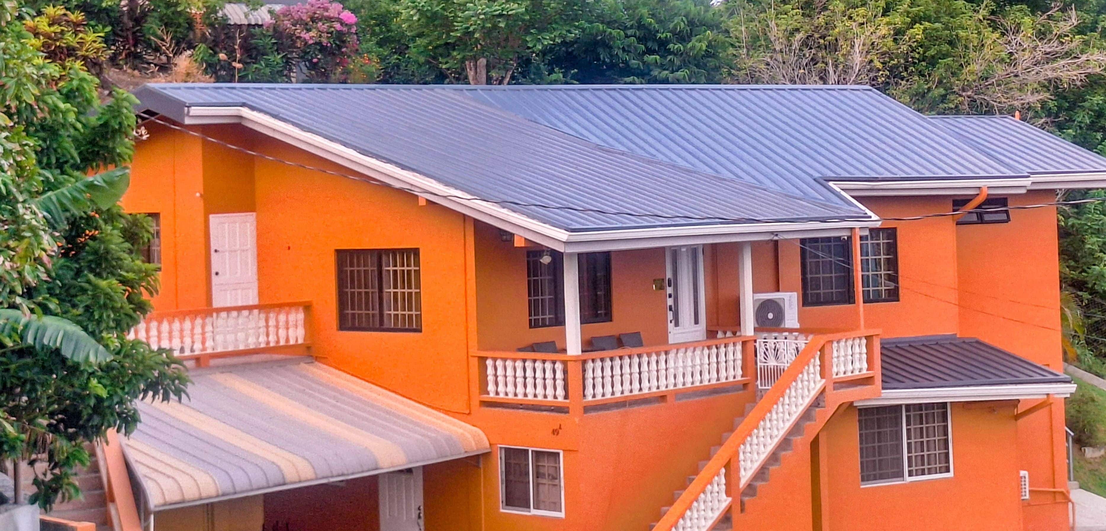 Un edificio de dos plantas con balcón, escaleras y techo de metal.