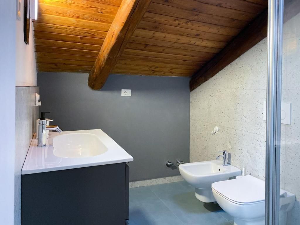 Un baño con techo de madera, un lavamanos blanco, un bidé y un inodoro.