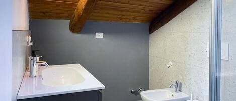 Un baño con techo de madera, un lavamanos blanco, un bidé y un inodoro.