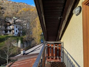 A wooden balcony with a view of a hillside and buildings. - AffittiPontediLegno - Panorama 3B (Temù)
