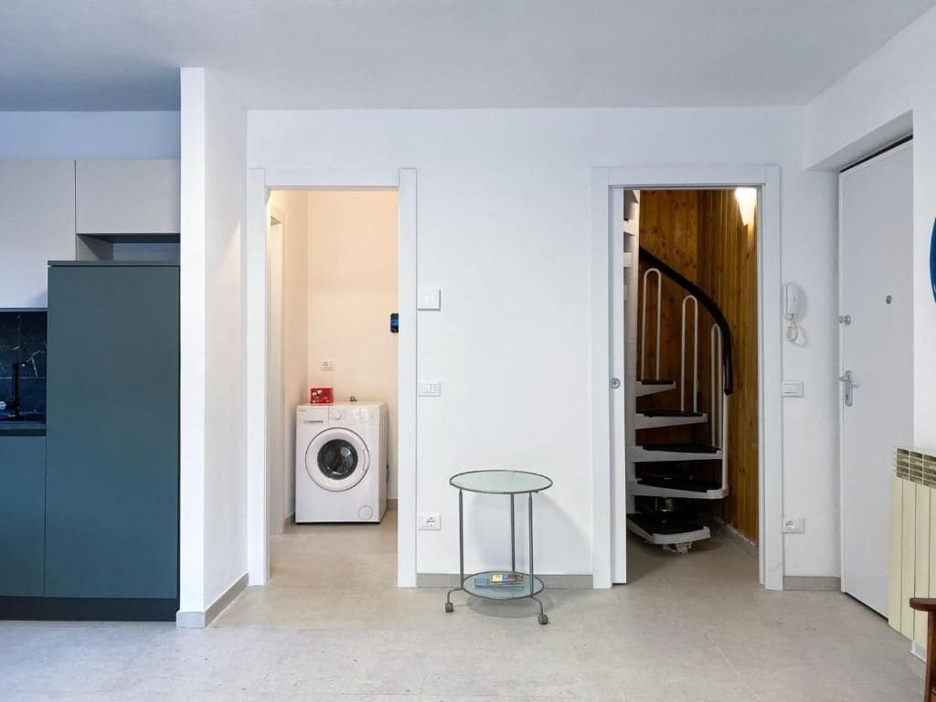 A modern kitchen with a washing machine and a small table in a hallway.
