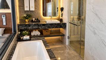 A modern bathroom with a large bathtub, a glass-enclosed shower, and marble flooring.