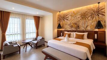 A hotel room with a large bed, a desk, a chair, and a bench.
