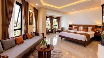 Habitación de hotel con una cama grande, un sofá, una mesita de centro y vistas al exterior.