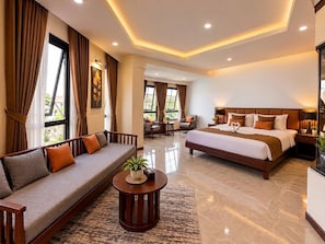 Habitación de hotel con una cama grande, un sofá, una mesita de centro y vistas al exterior.