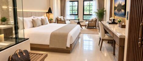 A modern hotel room with a large bed, a desk, a seating area, and a TV.