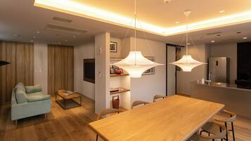 A modern living space with a dining area, kitchen, and a seating area with a sofa and coffee table.