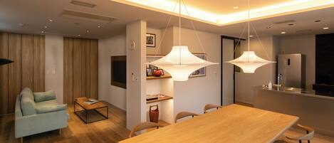 A modern living space with a dining area, kitchen, and a seating area with a sofa and coffee table.