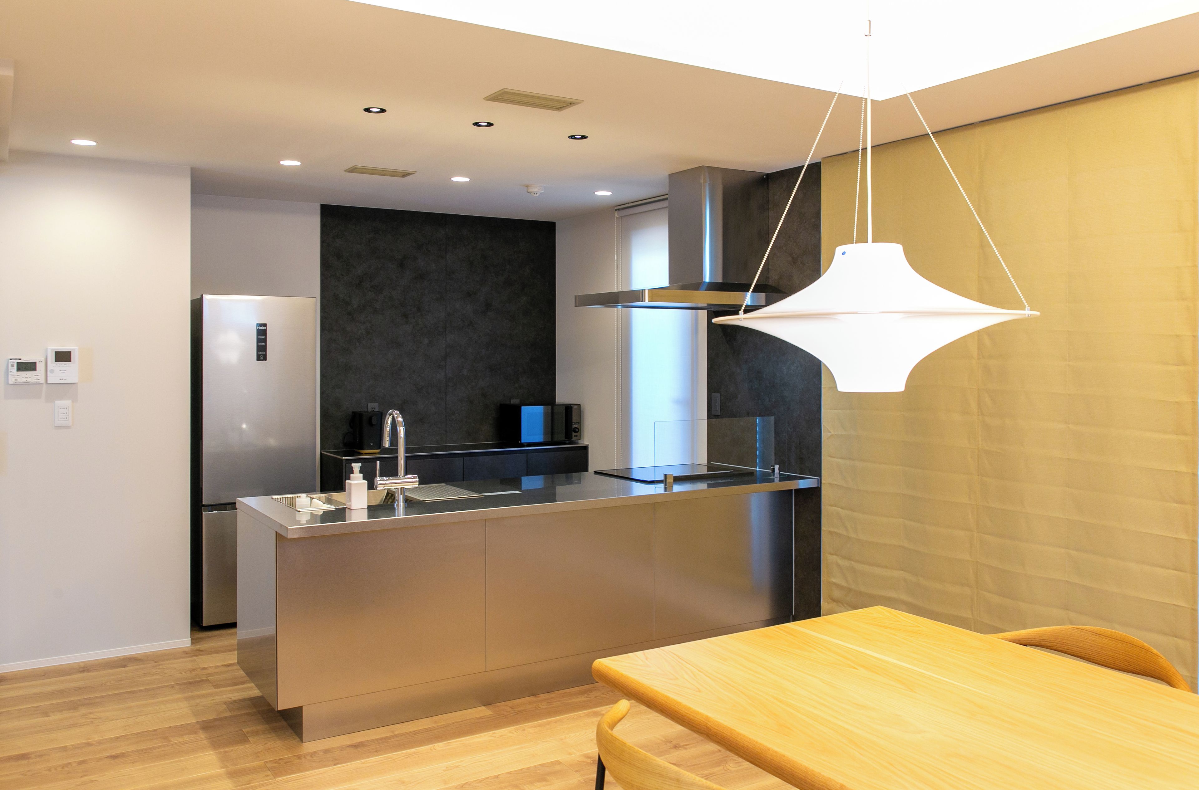 A modern kitchen with a central island, stainless steel appliances, and a pendant light.