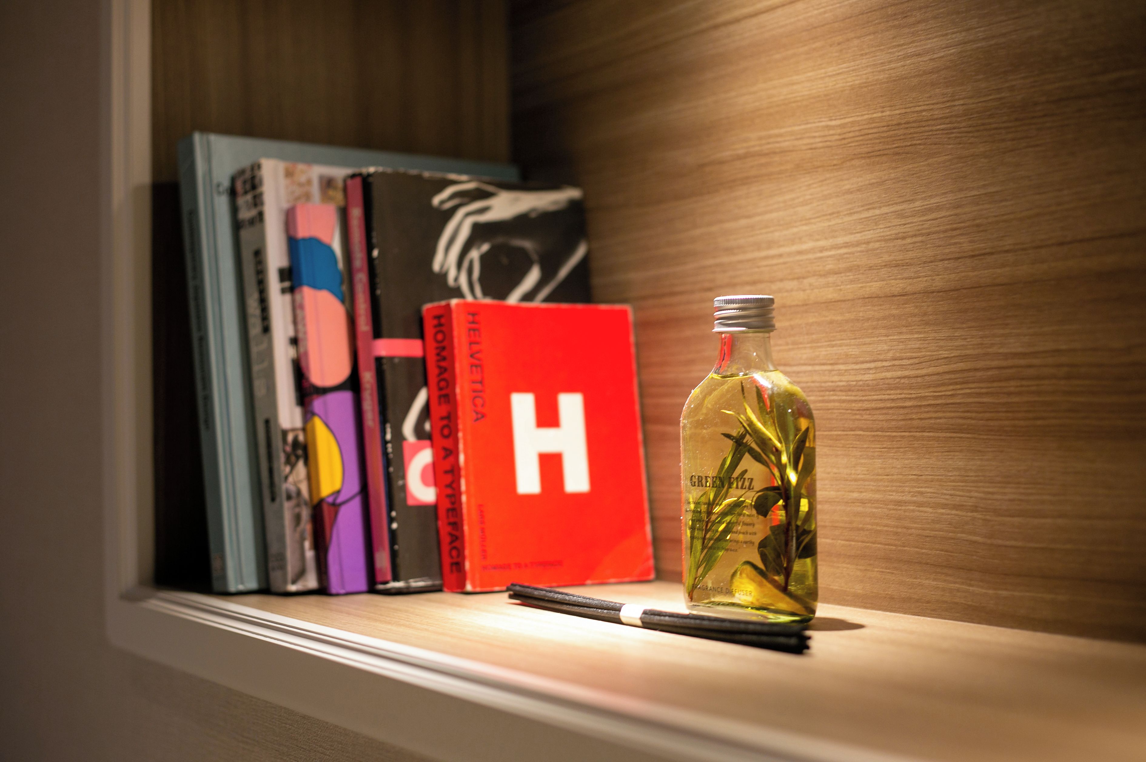 A shelf with books and a bottle of fragrance diffuser.