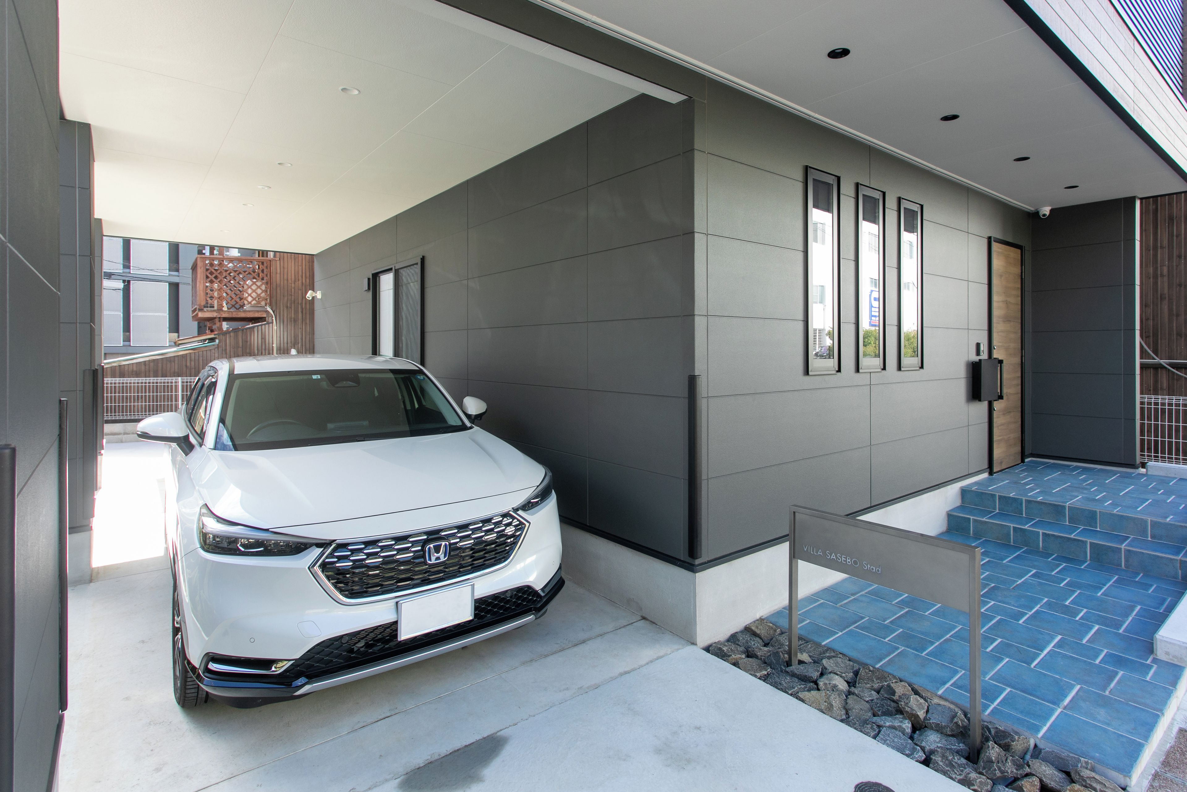 Un edificio moderno con un coche blanco estacionado frente a él.