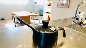 Una cocina con encimera de acero inoxidable, una olla negra con tapa y un posavasos de corcho.