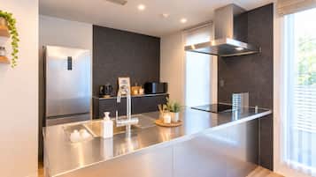 A modern kitchen with a stainless steel island, built-in appliances, and a large window providing natural light.