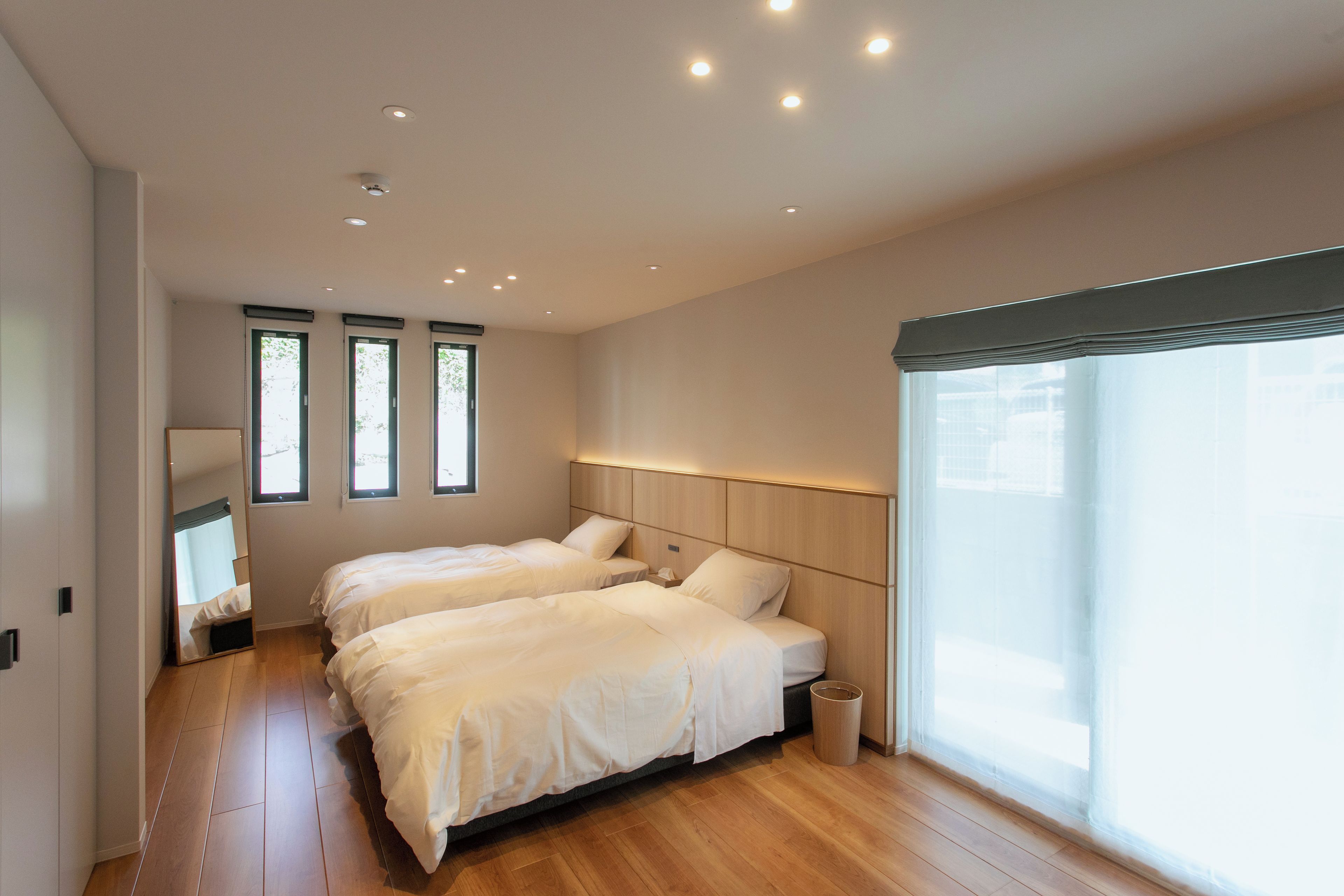 A hotel room with two beds, a large window, and a wooden floor.
