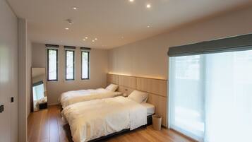 A hotel room with two beds, a large window, and a wooden floor.