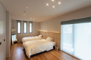 Habitación de hotel con dos camas, un ventanal grande y suelo de madera.