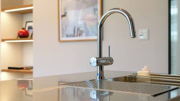 A modern kitchen with a stainless steel faucet, a reflective countertop, and a framed artwork on the wall.
