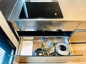 A kitchen with a built-in stove, stainless steel cabinets, and a drawer with various kitchen utensils.