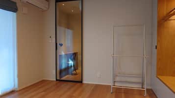 A room with a sliding glass door leading to a bathroom, a metal drying rack, and a wooden floor.