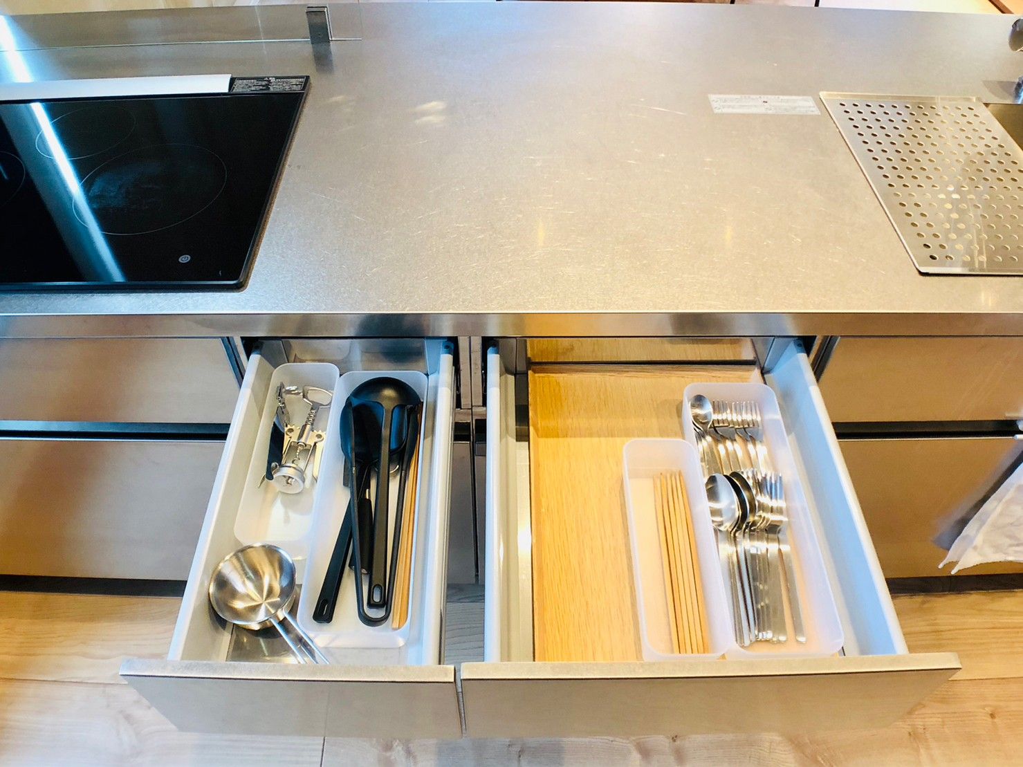 A stainless steel kitchen counter with a built-in induction cooktop and a perforated metal tray.