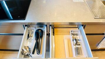 A stainless steel kitchen counter with a built-in induction cooktop and a perforated metal tray.