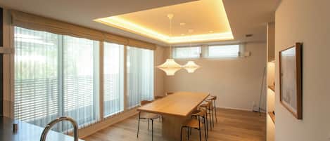 A modern kitchen with a wooden table and chairs, a stainless steel sink, and pendant lighting.