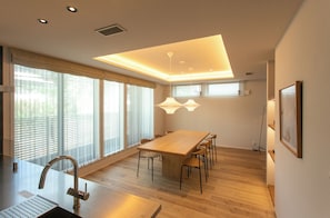 Una cocina moderna con una mesa y sillas de madera, un lavamanos de acero inoxidable e iluminación colgante.