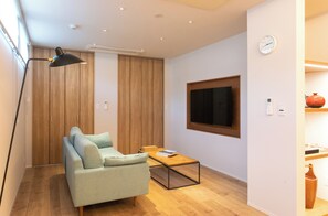 Una sala de estar moderna con un sofá, una mesa de centro, un televisor y un armario de madera.