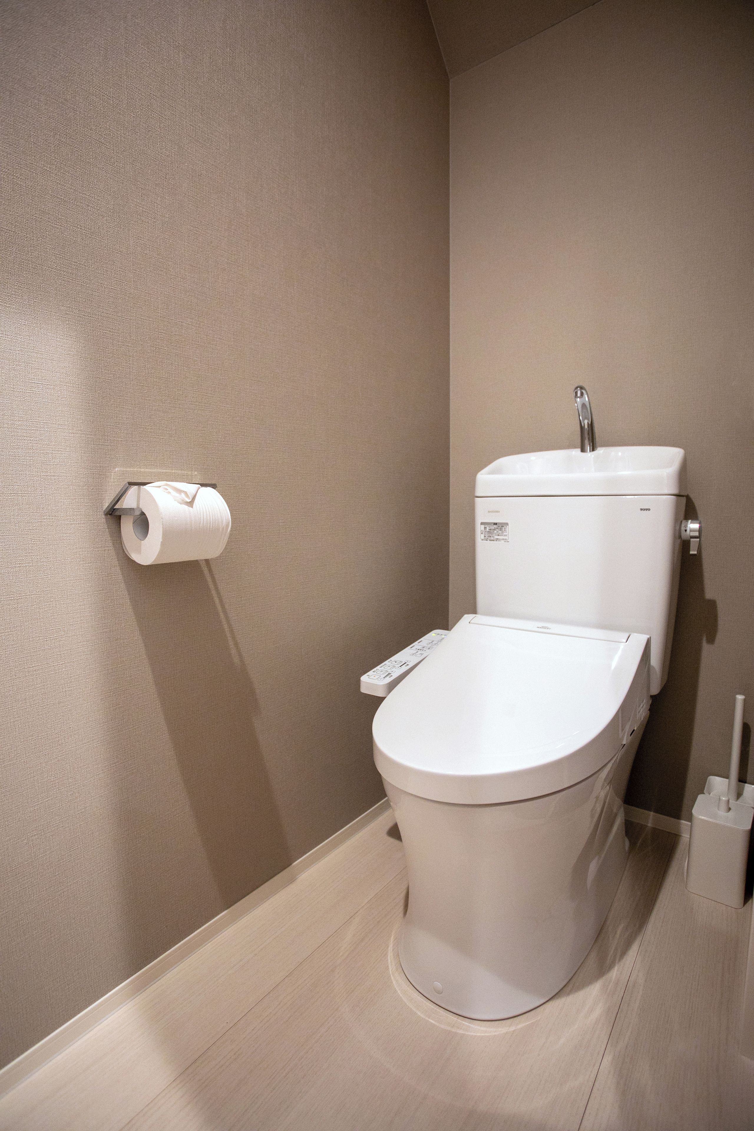 Un moderno WC con pannello di controllo, porta carta igienica a parete e funzione bidet.