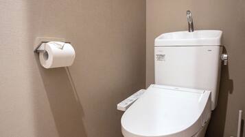 Un moderno WC con pannello di controllo, porta carta igienica a parete e funzione bidet.