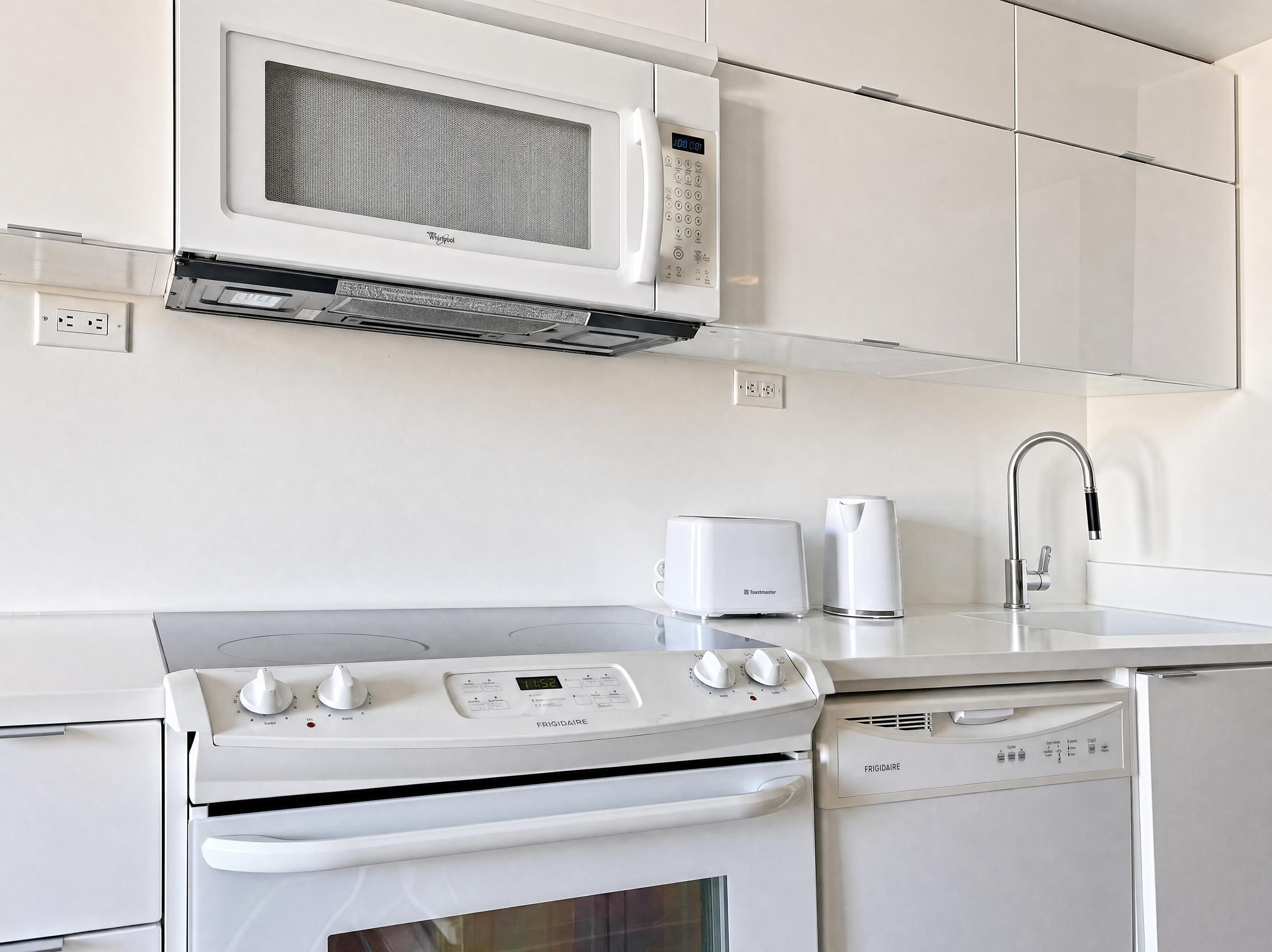 Een moderne keuken met een inbouw magnetron, broodrooster en vaatwasser.