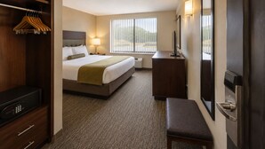 A hotel room with a bed, bedside table, lamp, TV, and a wardrobe. - Downtown Living Apartments (Toronto)