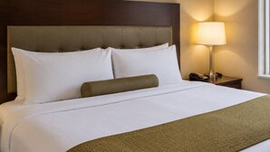 A hotel room with a bed, a headboard, a bedside lamp, and a nightstand. - Downtown Living Apartments (Toronto)