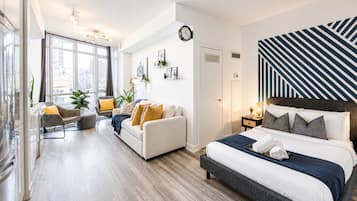 A modern bedroom with a large bed, a sofa, and a dining area.