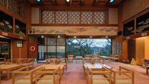 Une pièce de style japonais traditionnel, avec des tatamis, des meubles en bois et une vue dégagée sur l’extérieur grâce à de grandes fenêtres.
