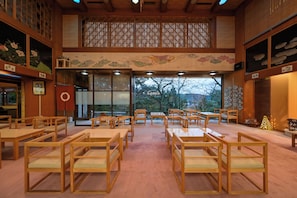 Ett traditionellt japanskt rum med tatamimattor, trämöbler och utsikt genom stora fönster.