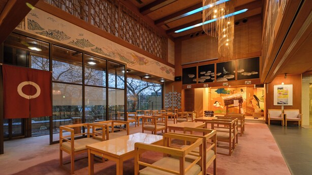 Un intérieur de style japonais traditionnel, avec un sol recouvert de tatamis, des meubles en bois et des œuvres d’art accrochées aux murs.