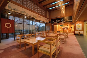 Un interior tradicional al estilo japonés, con suelo de tatami, muebles de madera y obras de arte en las paredes.