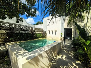 A swimming pool with a geometric design, surrounded by lush greenery and a white building with decorative lattice. - House 54, Mérida (Mérida)