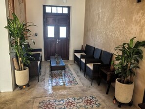 A room with a dark wooden door, wicker furniture, a patterned floor, and potted plants. - House 54, Mérida (Mérida)