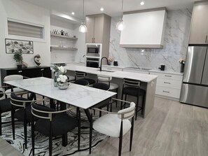 A modern kitchen with a central island, stainless steel appliances, and pendant lighting.