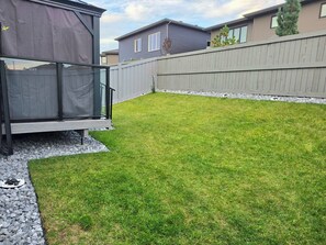 A backyard with a fenced area, a small shed, and a grassy lawn.