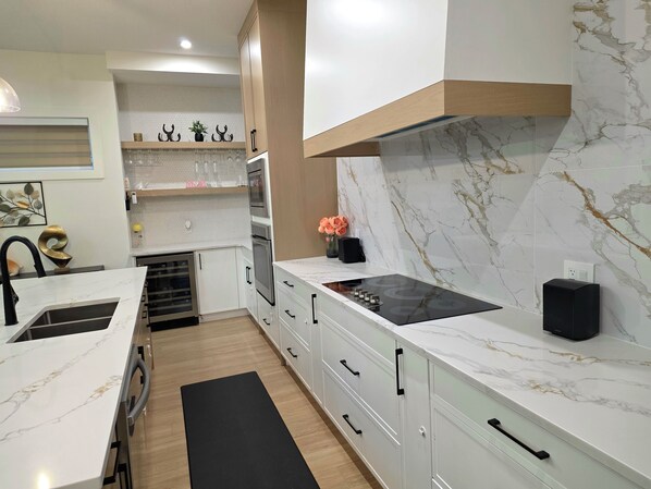 A modern kitchen with white cabinetry, a black countertop, and a built-in oven.