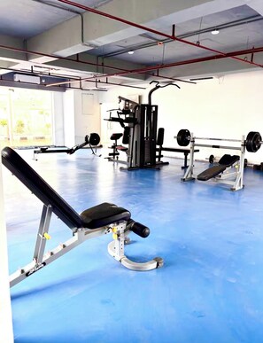 Ein Fitnessstudio mit unterschiedlichen Trainingsgeräten, darunter Bänke und Kraftgeräte.