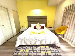 A hotel room with a bed, bedside tables, a chair, and a patterned rug. - Serene Luxe Studio - Pool & Gym (Gurugram)