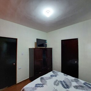 A room with a bed, a television on a cabinet, and two doors. - Casa Ju (Pet-Friendly) (Ciudad Valles)