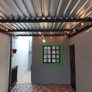 A corridor with a tiled floor, a green-framed window, and hanging lights. - Casa Ju (Pet-Friendly) (Ciudad Valles)