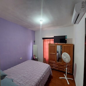 A bedroom with a bed, a wardrobe, a television, a fan, and an air conditioning unit. - Casa Ju (Pet-Friendly) (Ciudad Valles)